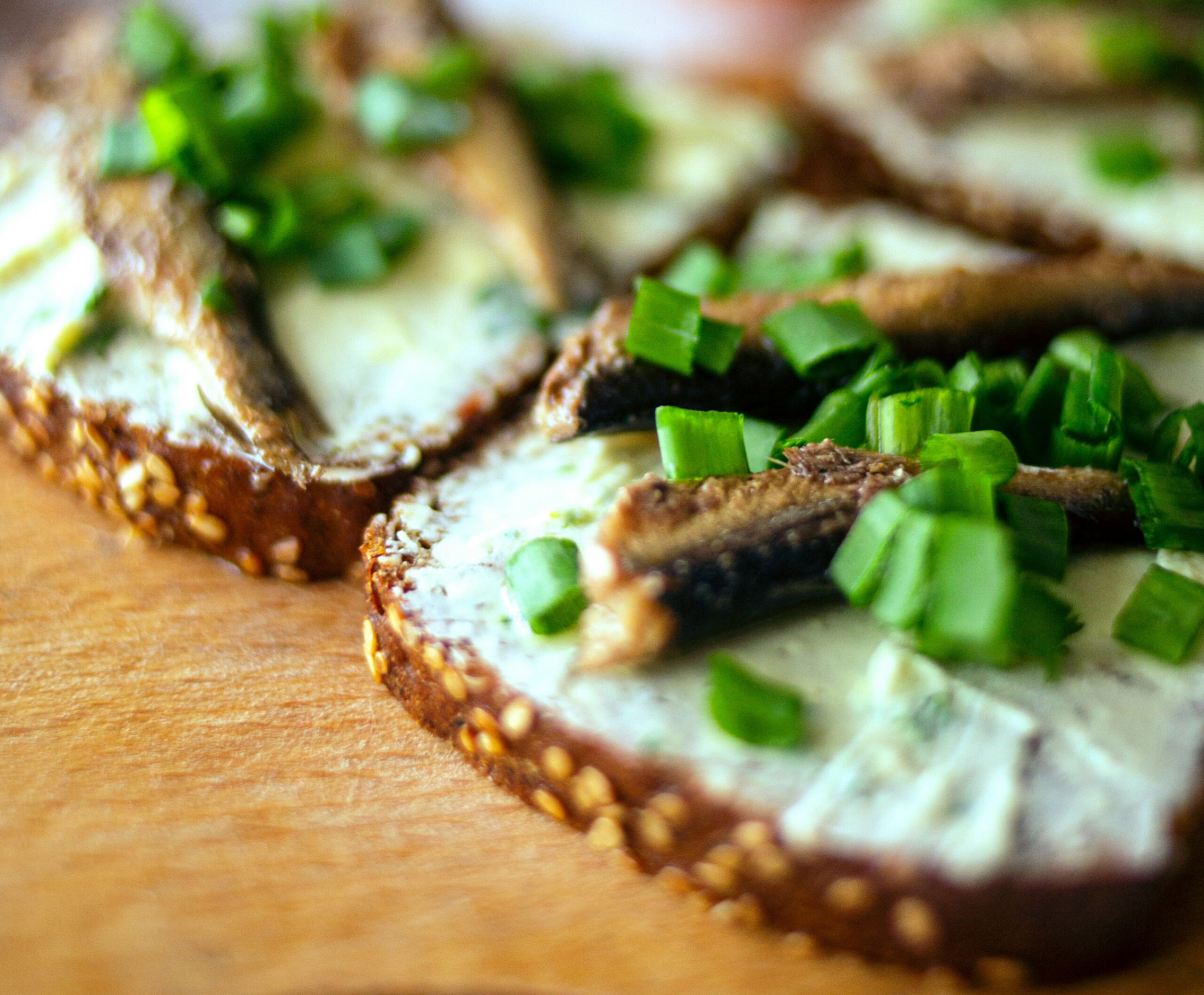 Close up of toast with spread and spring onions on a wood board