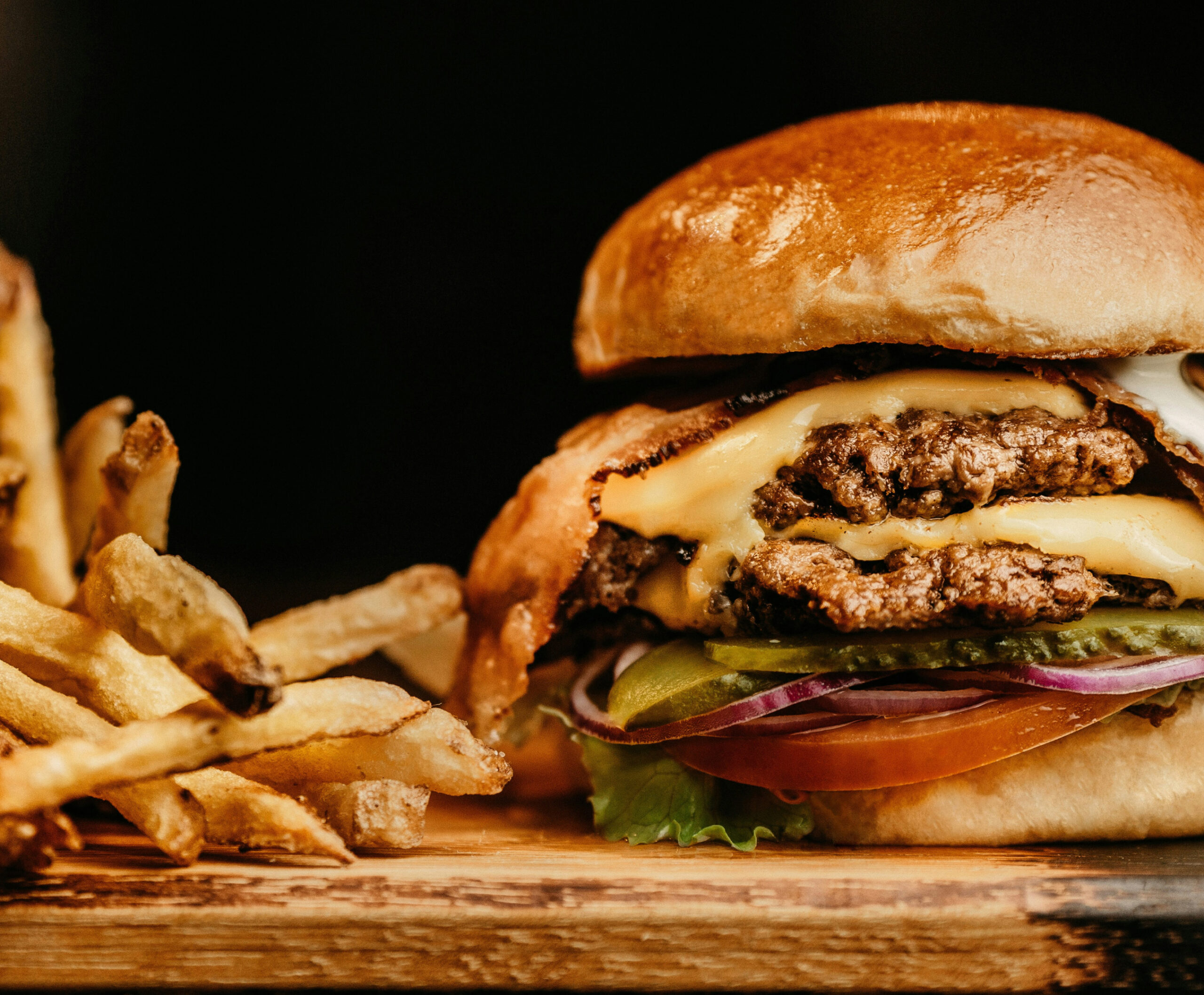 Close up of cheeseburger and french fries on wood board