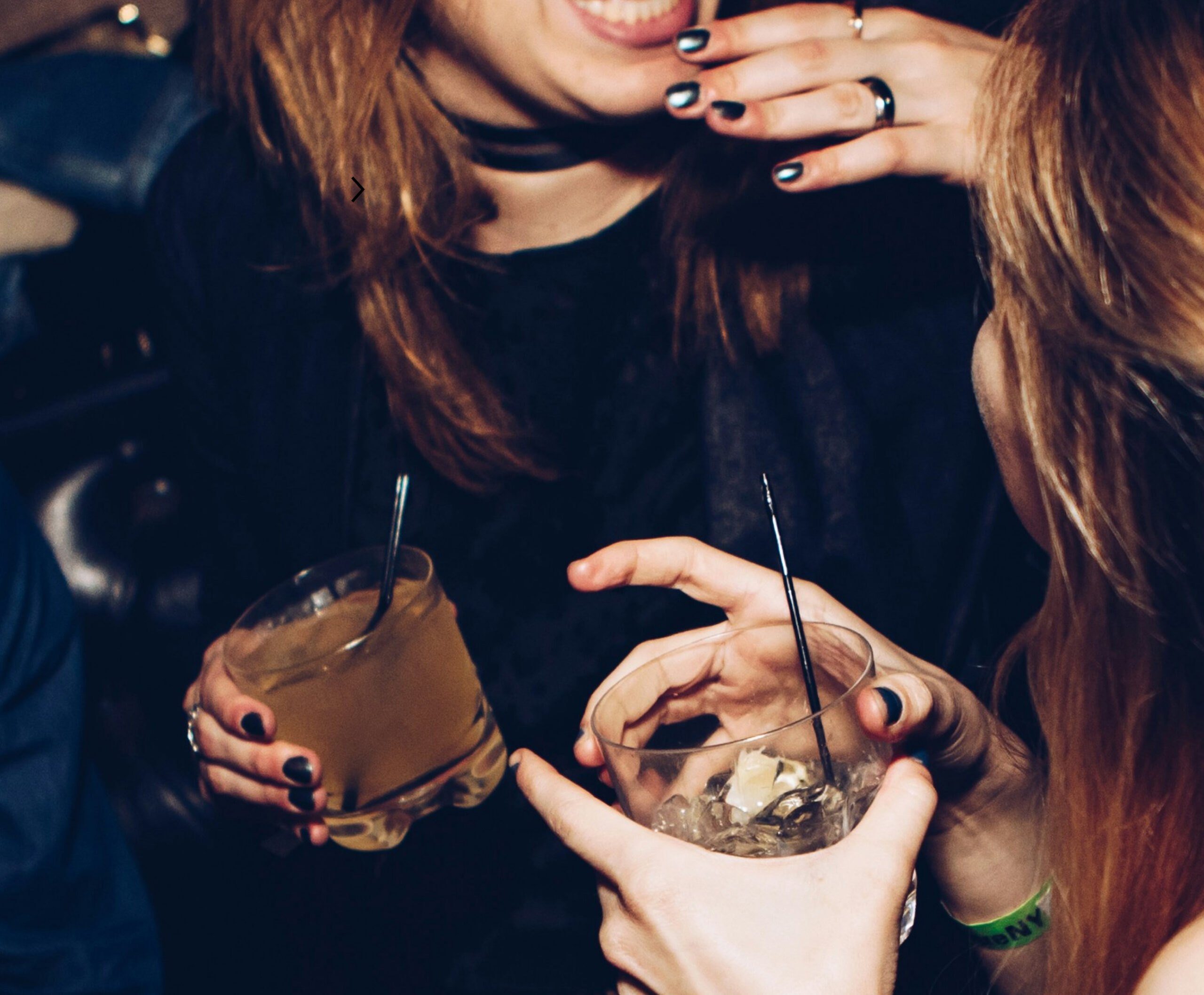 Women holding drinks and chatting in a bar setting
