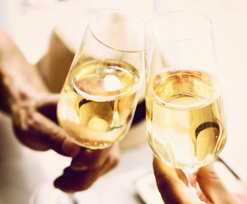 Two flutes filled with prosecco held by two hands in a toast