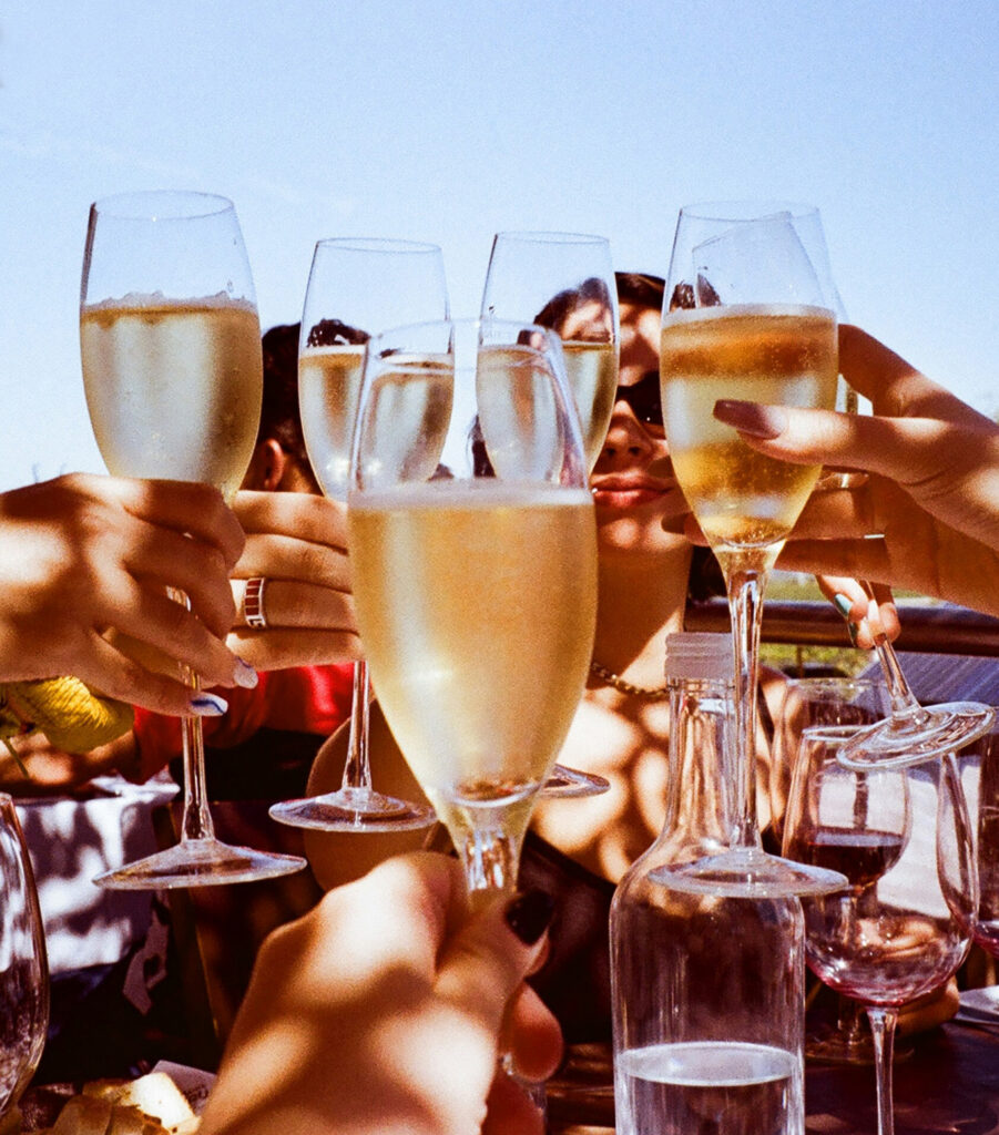 Sunny scene of many hands making a toast with flutes filled with Prosecco